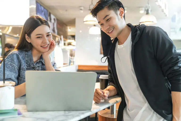 ลูกค้าสองคนนั่งดูหน้าเว็บไซต์ร้านค้าบนโน้ตบุ๊กด้วยกันในร้านกาแฟ
